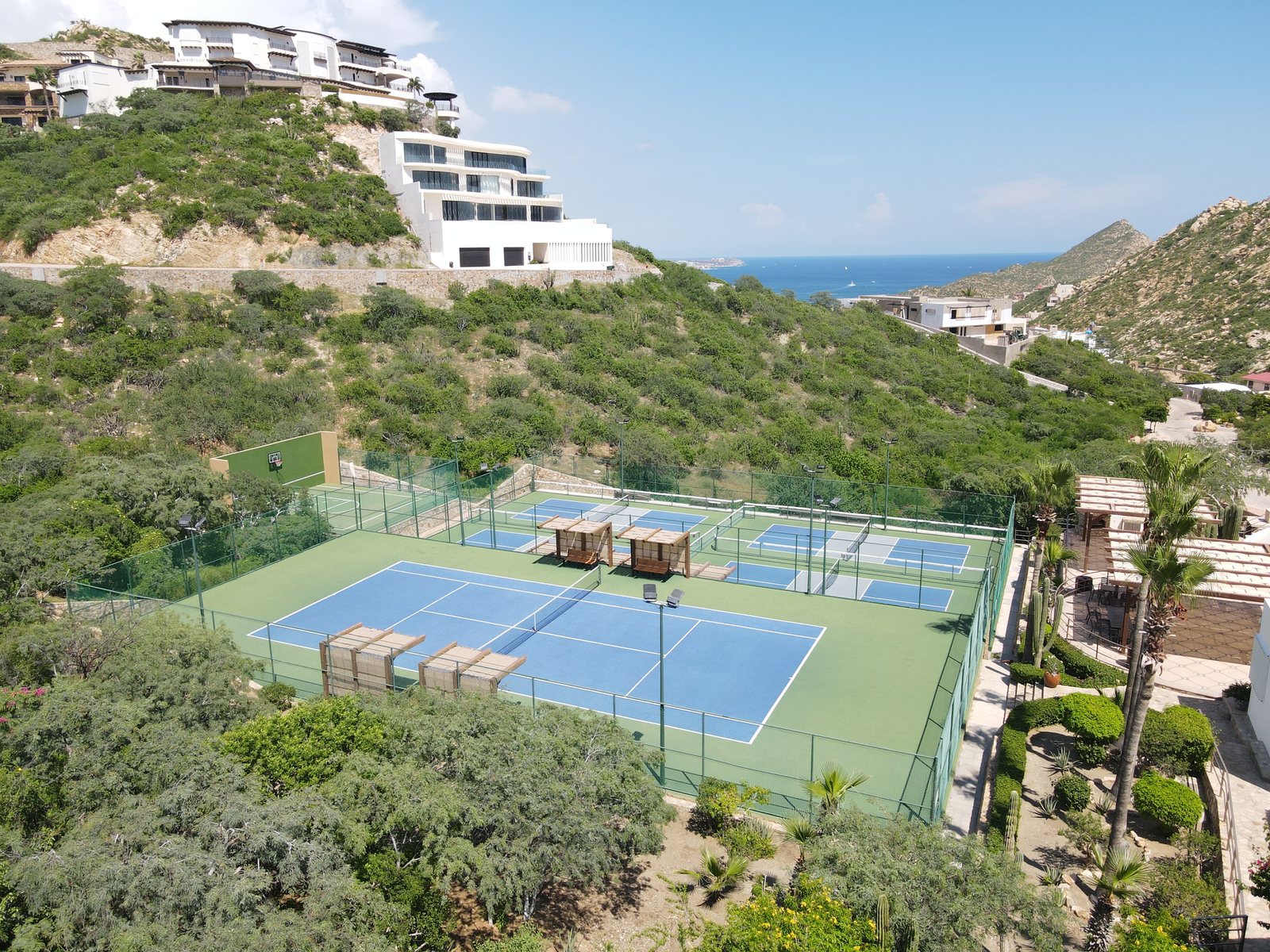 Tennis and pickleball courts terraced into the Pedregal hillside above the Pacific