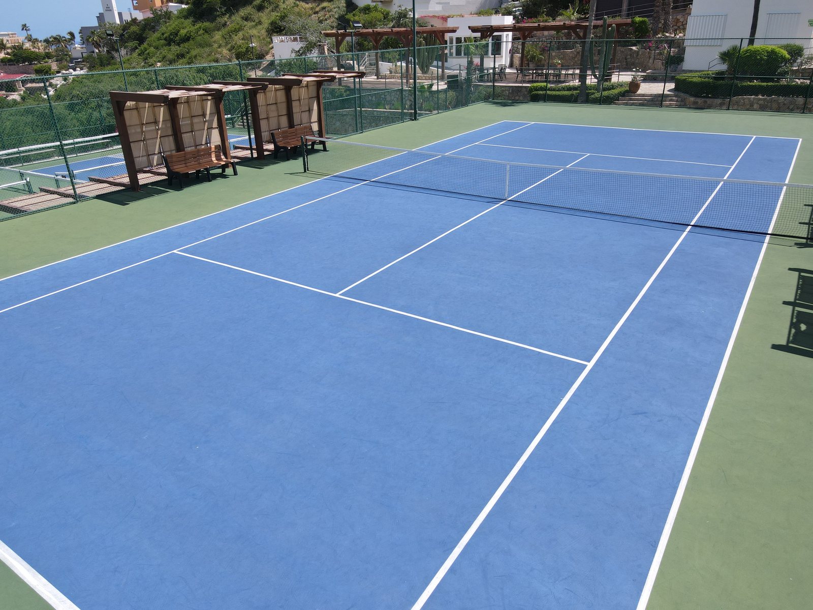 Full size tennis court at Pedregal with shaded seating and floodlights